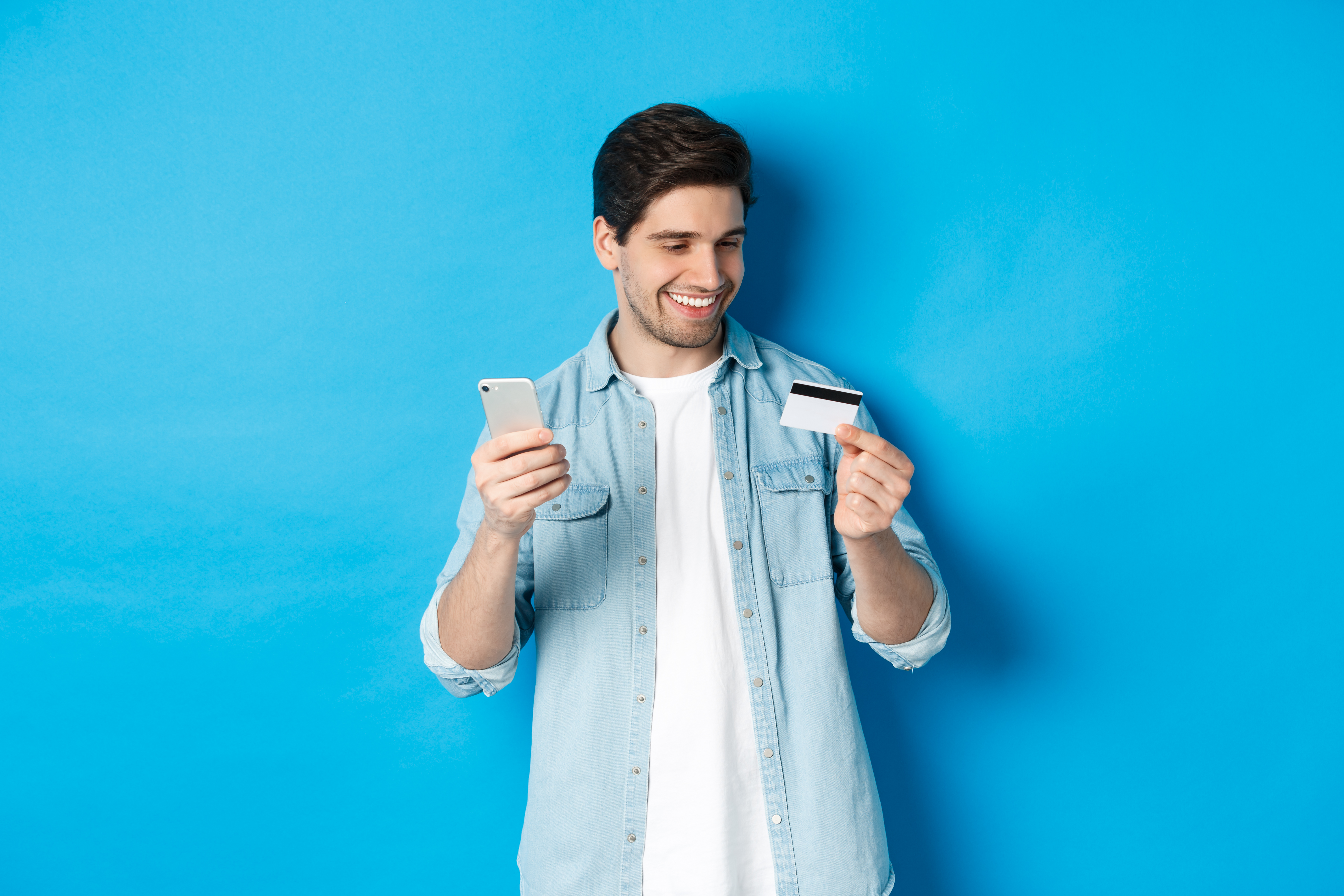 A photo of a man holding a credit card and smartphone, representing Top Up GoPay from BCA.